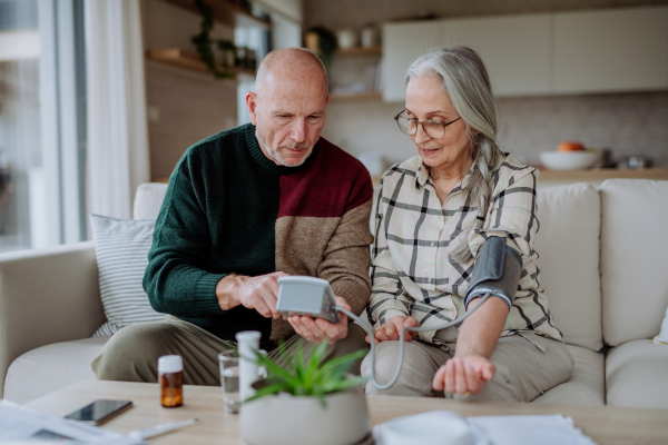 A senior couple at home measuring blood pressure.