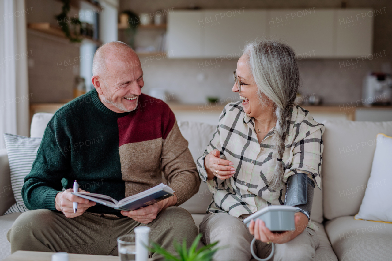 A senior couple at home measuring blood pressure.