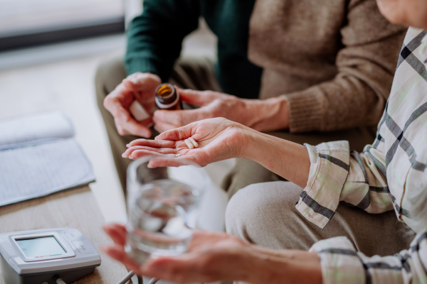 A close-up of senior man giving his wife medication at home