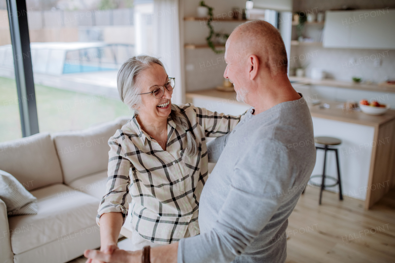 A cheerful senior couple dancing together at home.