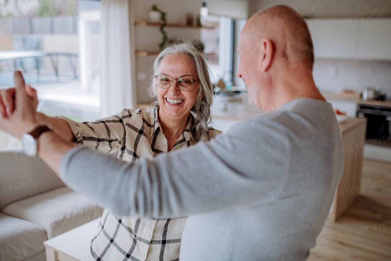 A cheerful senior couple dancing together at home.