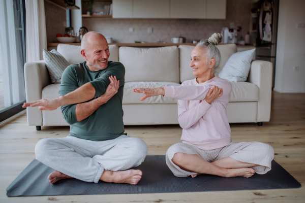 A senior couple doing relaxation exercise together at home.