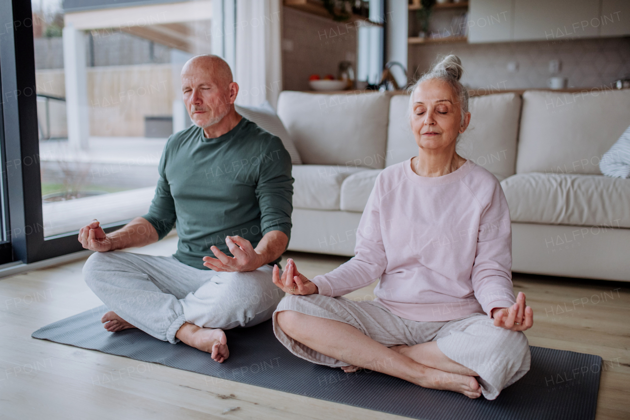 A senior couple doing relaxation exercise together at home.