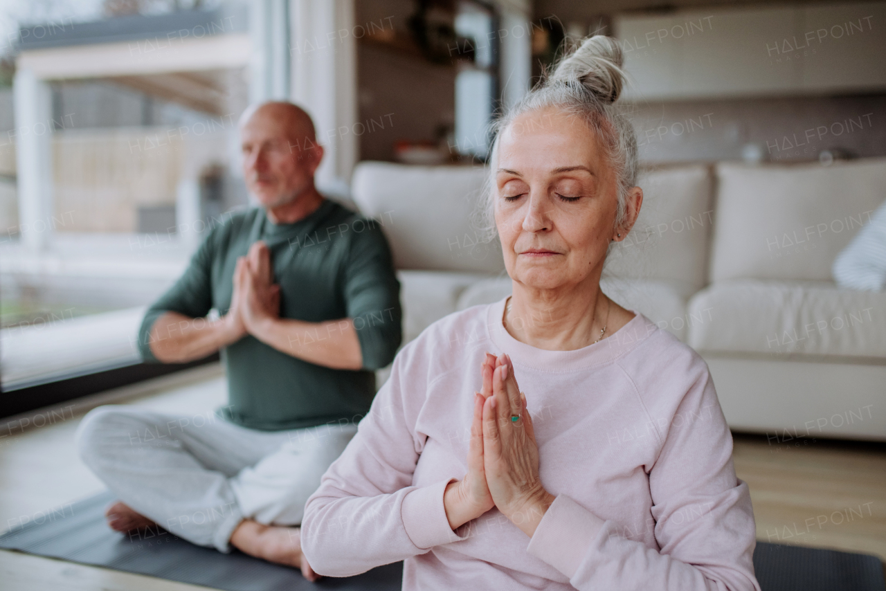 A senior couple doing relaxation exercise together at home.