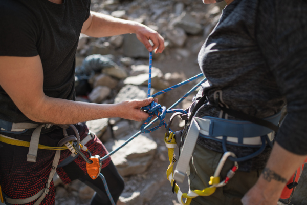 An unrecognizable instructor with senior woman getting ready for climbing rocks outdoors in nature, active lifestyle.