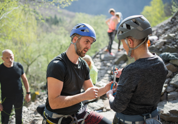 A group of seniors with instructor climbing rocks outdoors in nature, active lifestyle.