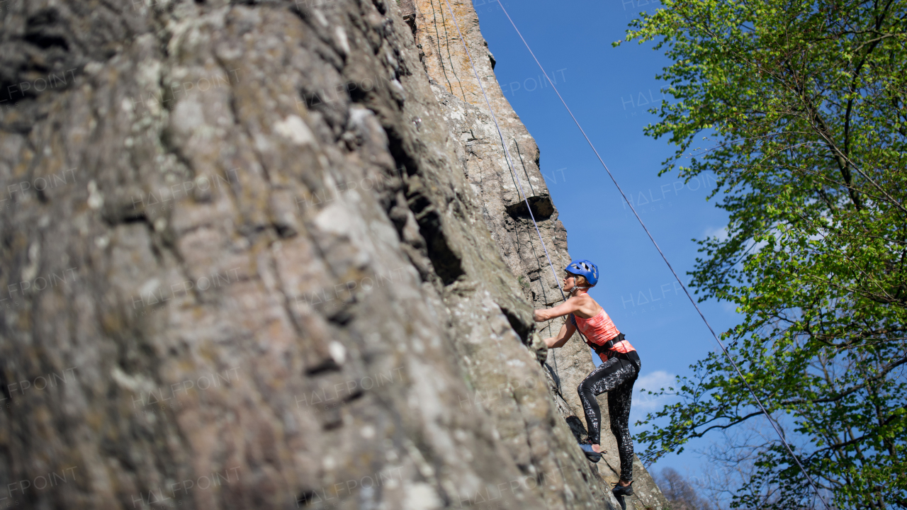 Mid adult woman climbing rocks outdoors in nature, an active lifestyle.