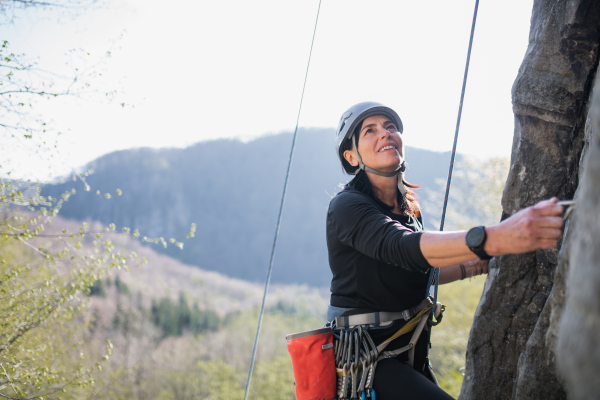 Portrait of senior woman climbing rocks outdoors in nature, active lifestyle.