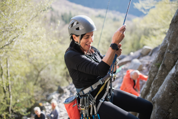 Portrait of senior woman climbing rocks outdoors in nature, active lifestyle.