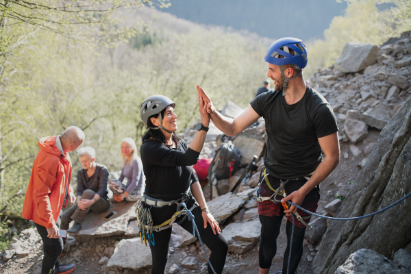 A group of seniors with instructor climbing rocks outdoors in nature, active lifestyle.