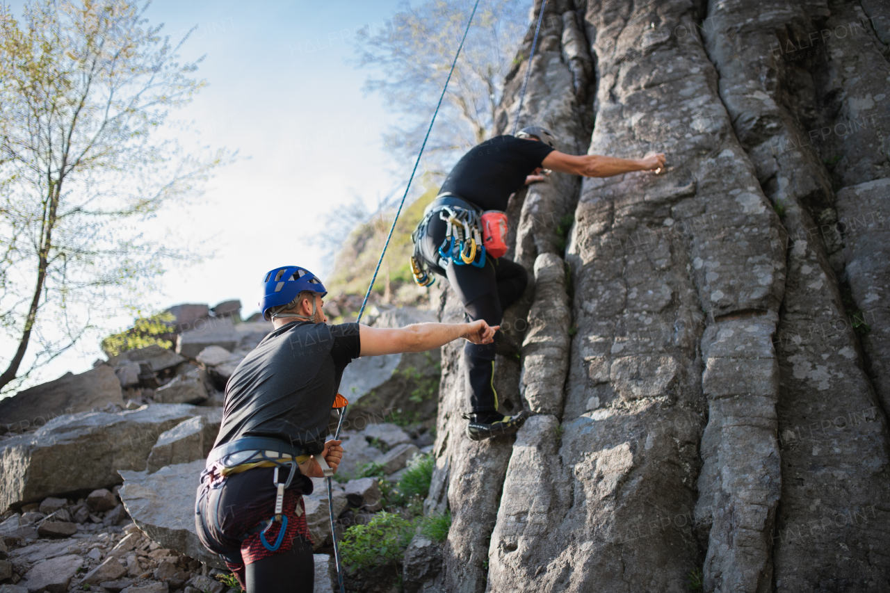 Portrait of senior man with instructor climbing rocks outdoors in nature, active lifestyle.