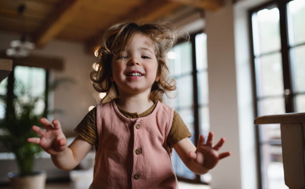 A happy small girl jumping at home, looking at camera.