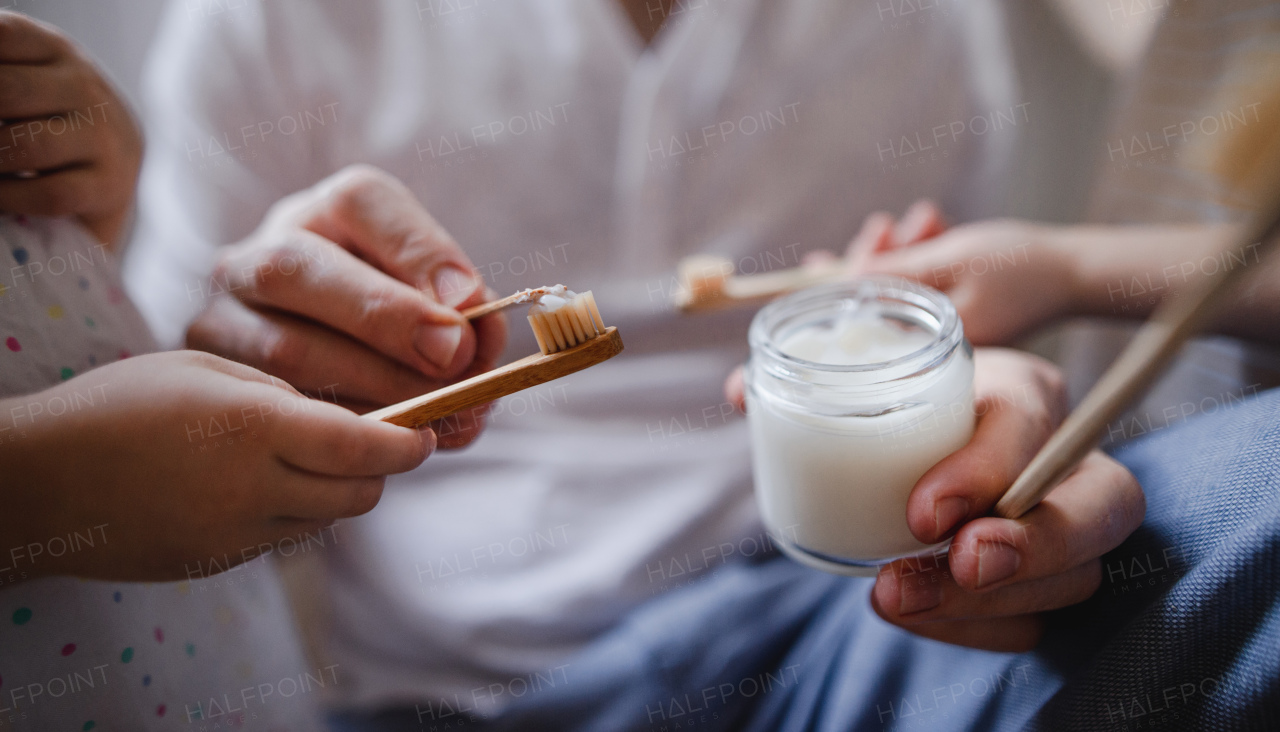 Hands of an unrecognizable father with two small children brushing teeth indoors at home, sustainable lifestyle concept.