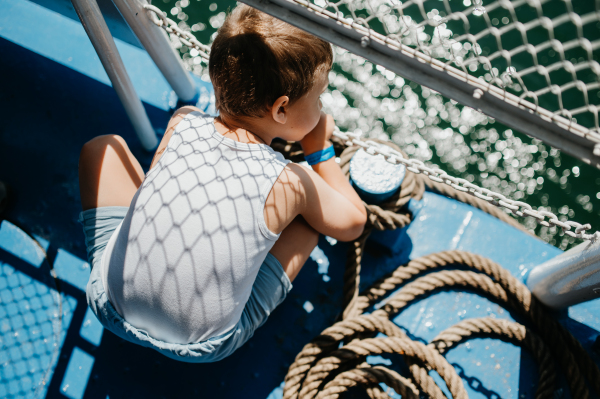 A little curious boy looking at water from motor boat.