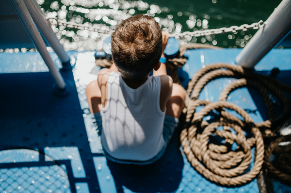 A little curious boy looking at water from motor boat.