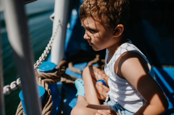 A little curious boy looking at water from motor boat.