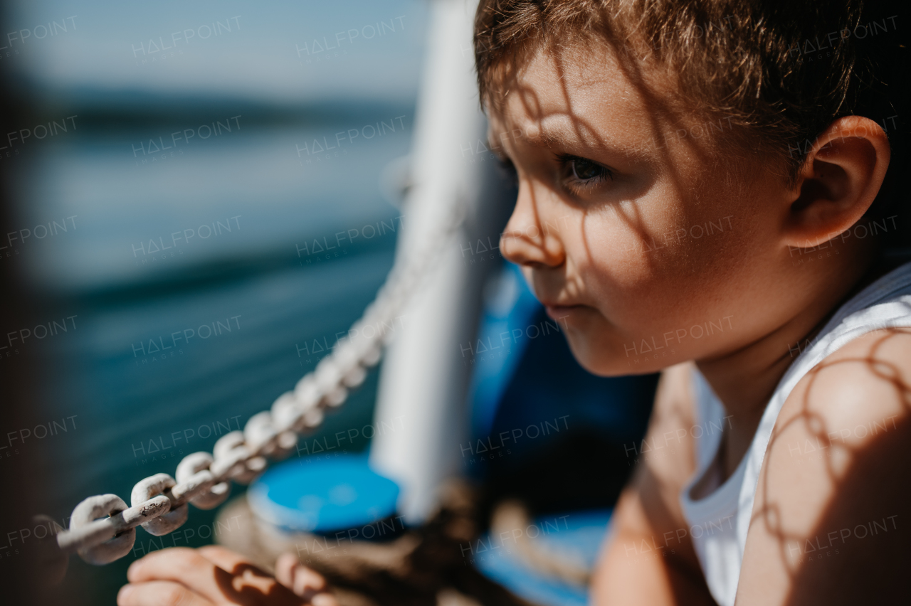 A little curious boy looking at water from motor boat.