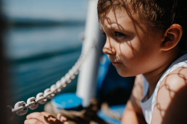 A little curious boy looking at water from motor boat.