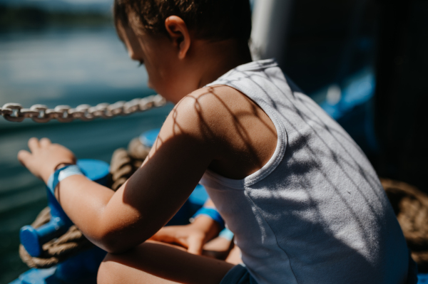 A little curious boy looking at water from motor boat.