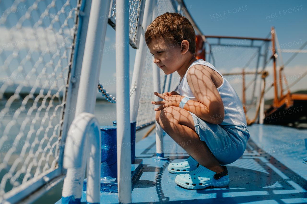 A little curious boy looking at water from motor boat.