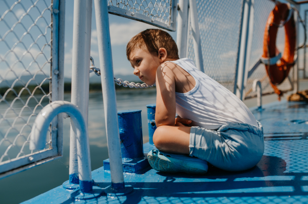 A little curious boy looking at water from motor boat.