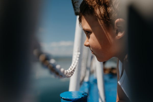 A little curious boy looking at water from motor boat.