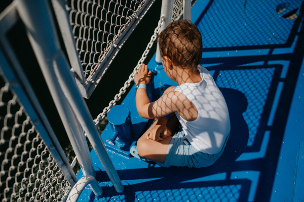 A little curious boy looking at water from motor boat.