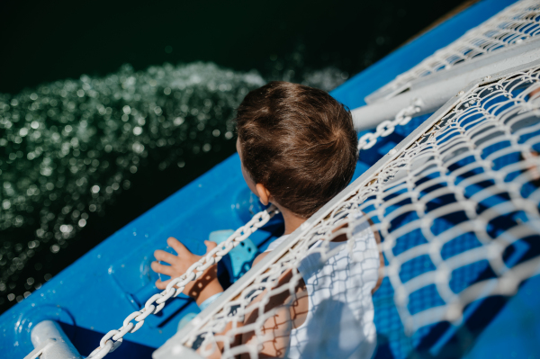 A little curious boy looking at water from motor boat.