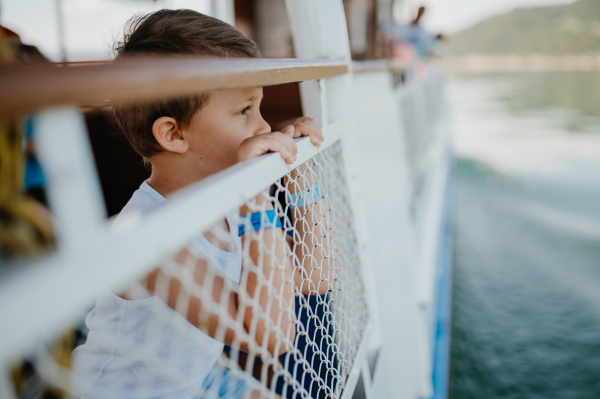 A little curious boy looking at water from motor boat.