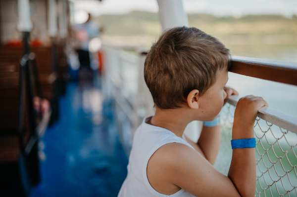 A little curious boy looking at water from motor boat.