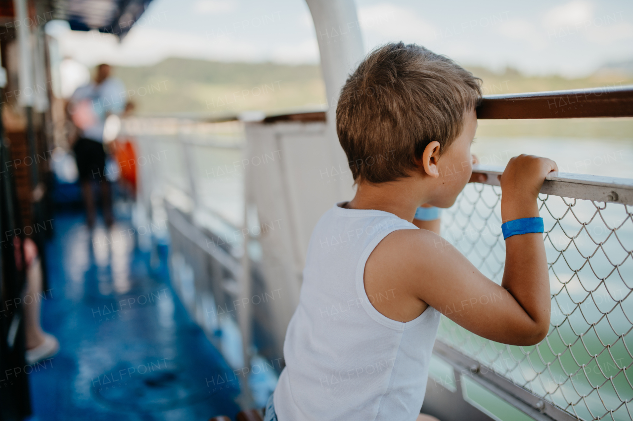 A little curious boy looking at water from motor boat.