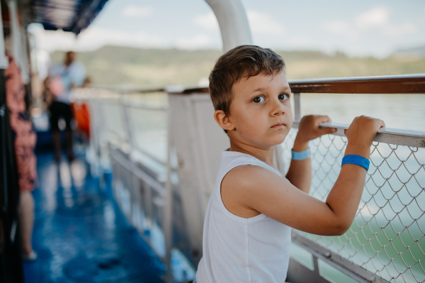 A little curious boy looking at water from motor boat.