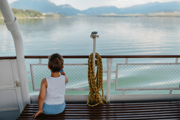 A little curious boy looking at water from motor boat.