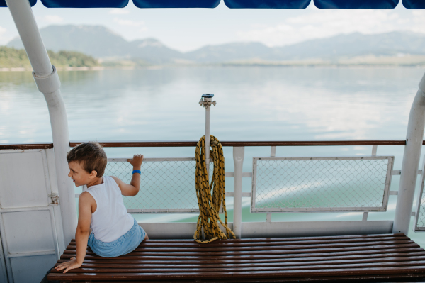 A little curious boy looking at water from motor boat.