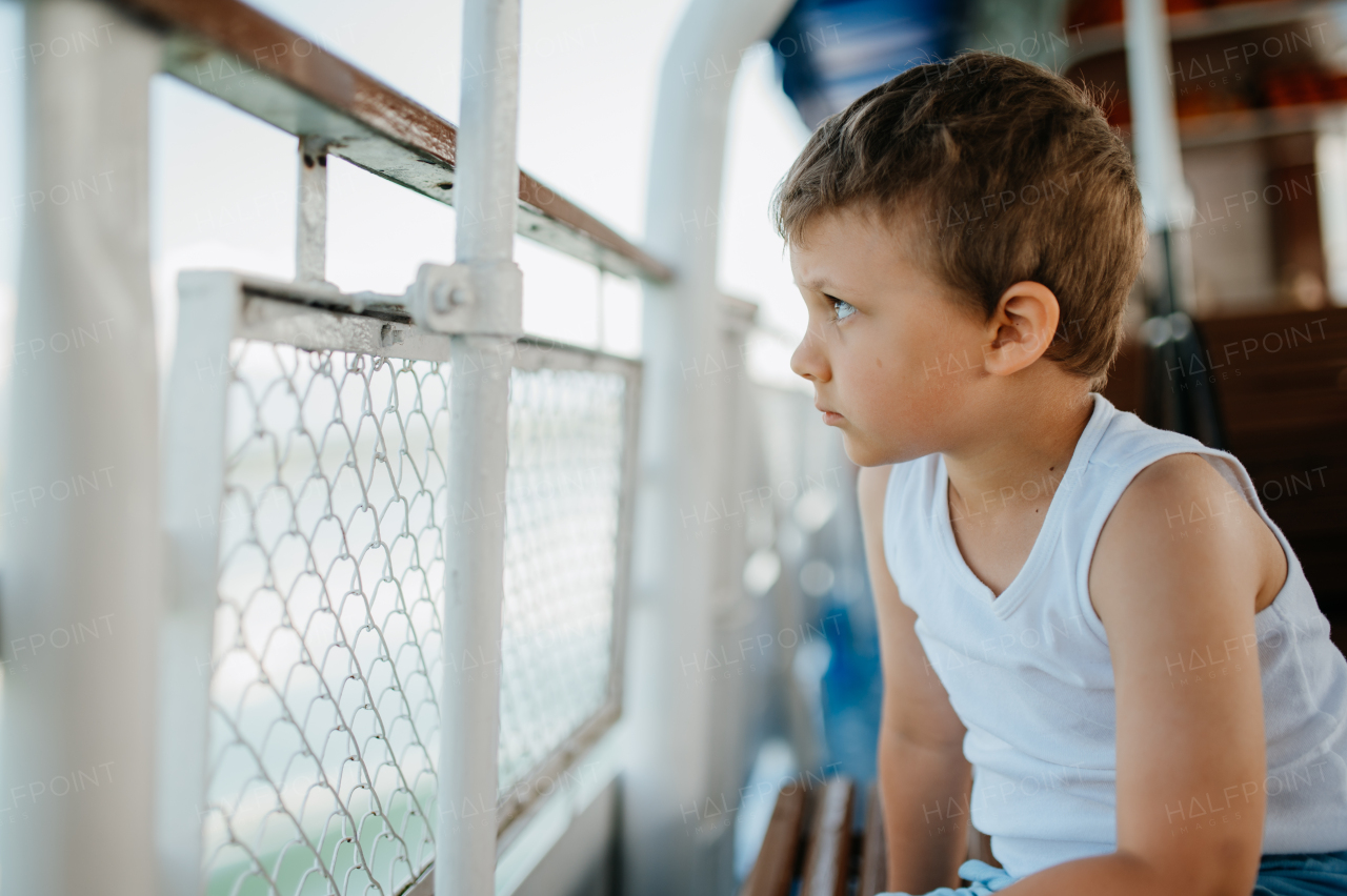 A little curious boy on summer cruise on sea with motor boat.