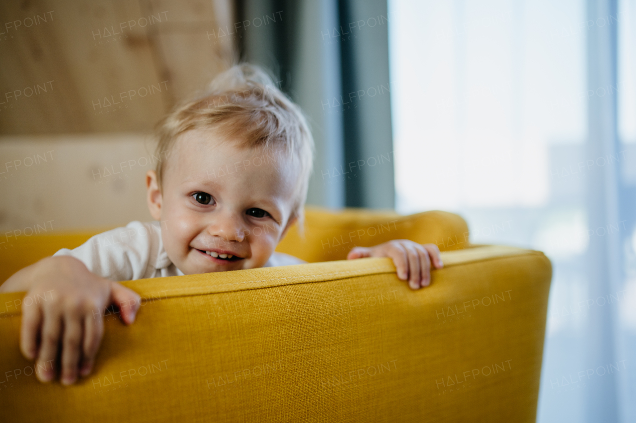 A little curious girl sitting on sofa and looking at camera.