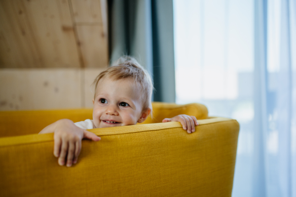 A little curious girl sitting on sofa and looking at camera.