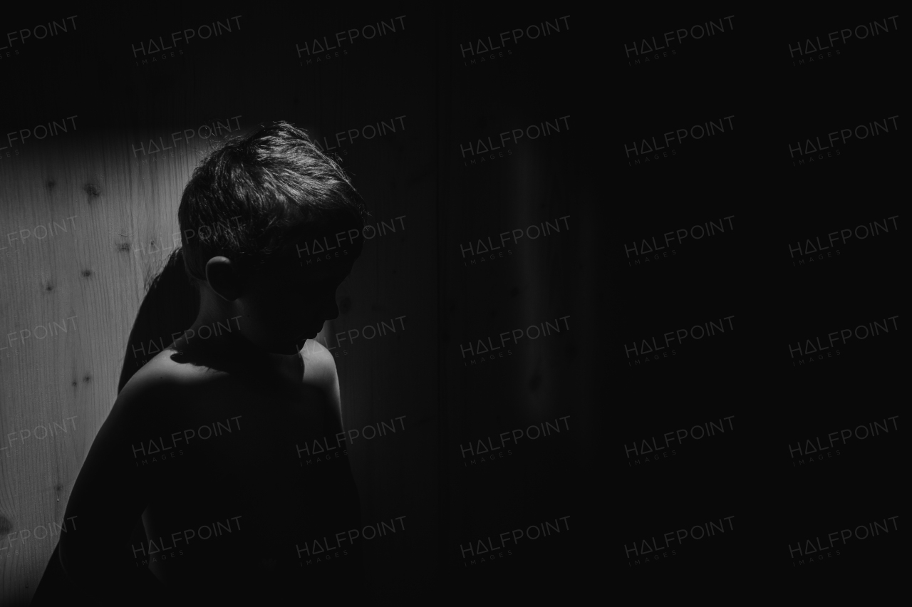 A black and white portrait of sad anonymous little boy