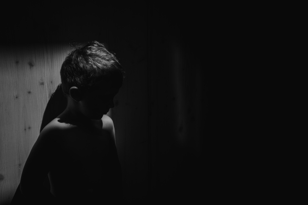 A black and white portrait of sad anonymous little boy