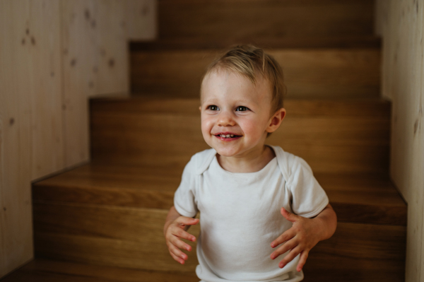 A cute little girl sitting on stairs at home.