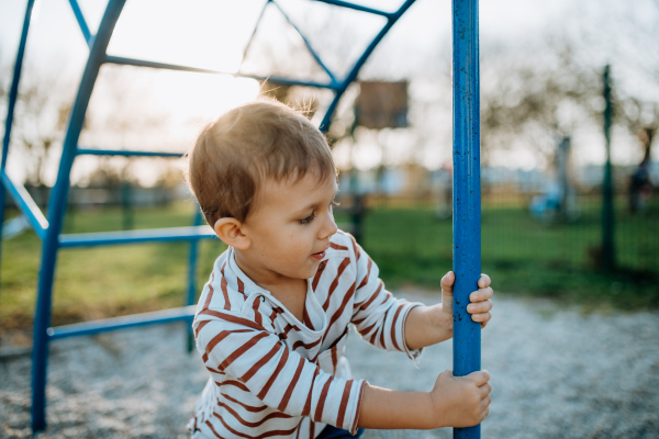 A little boy playing on an outdoor playground.