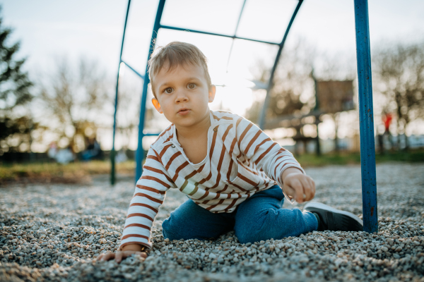 A little boy playing on an outdoor playground.