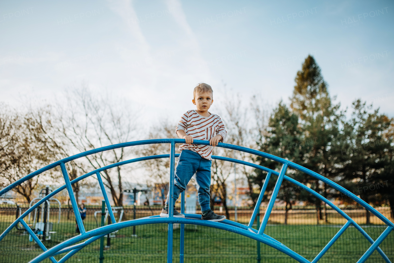 A little boy playing on an outdoor playground.