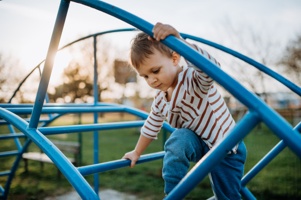 A little boy playing on an outdoor playground.