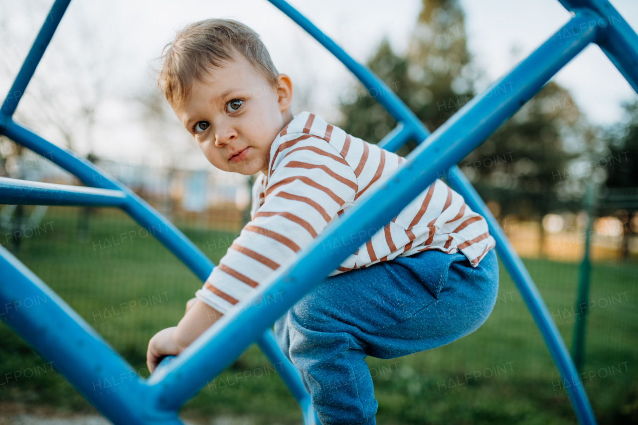 A little boy playing on an outdoor playground.