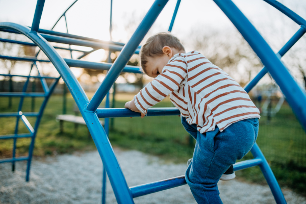 A little boy playing on an outdoor playground.