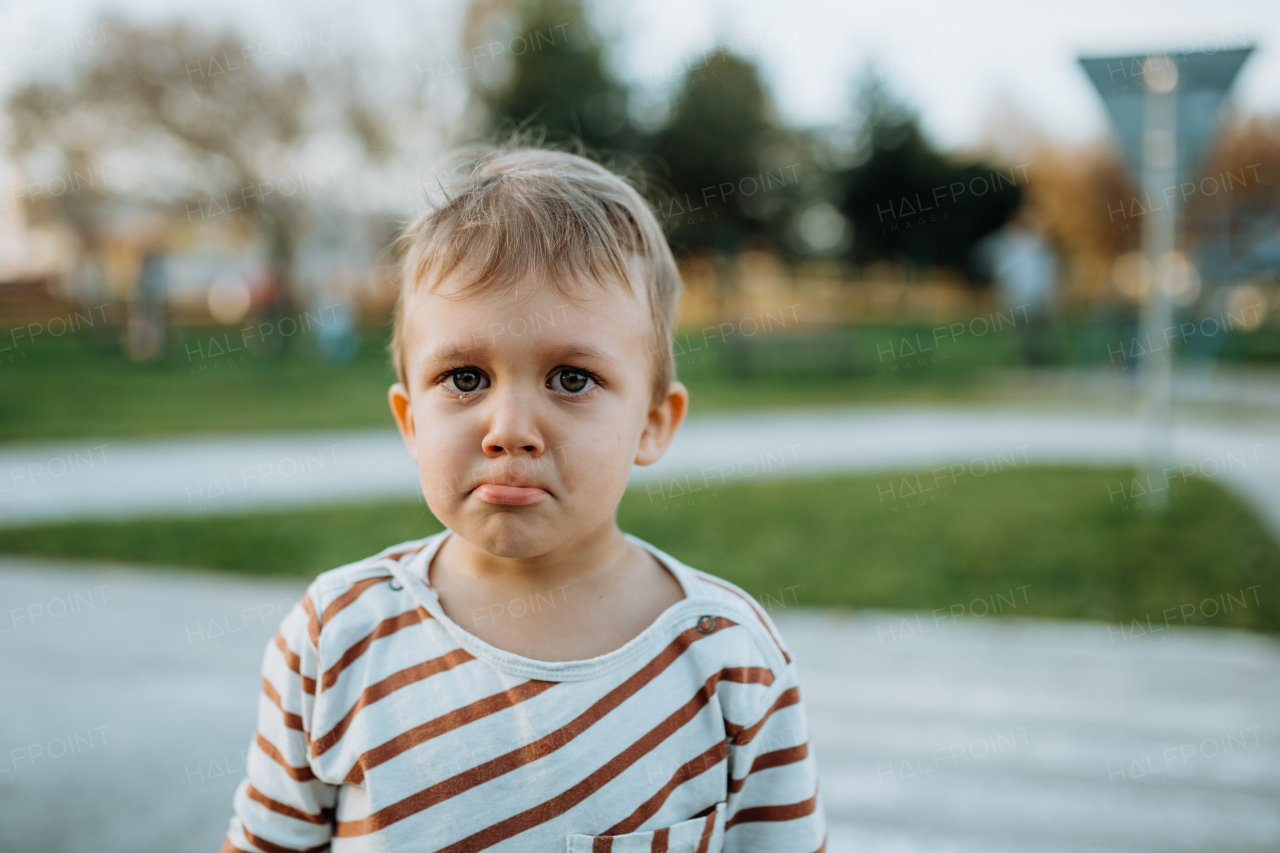 A sad little boy crying outside in park