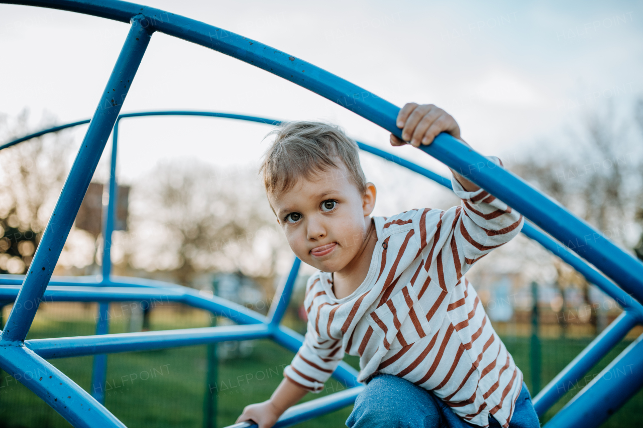 A little boy playing on an outdoor playground.