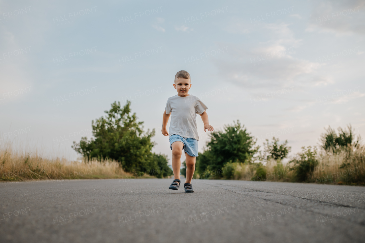 A little boy is running on road in summer