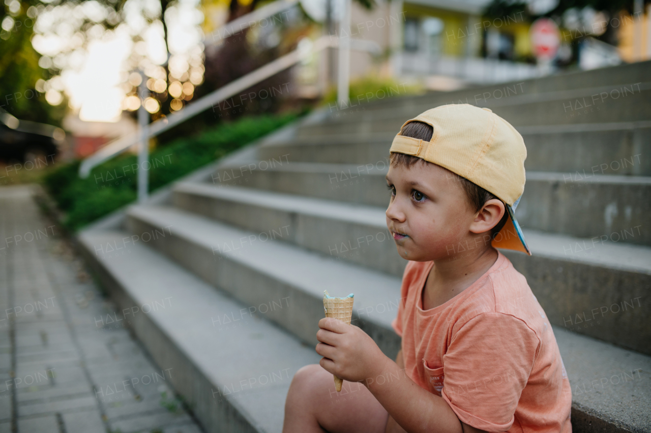 A little cute boy with ice cream outdoors in summer